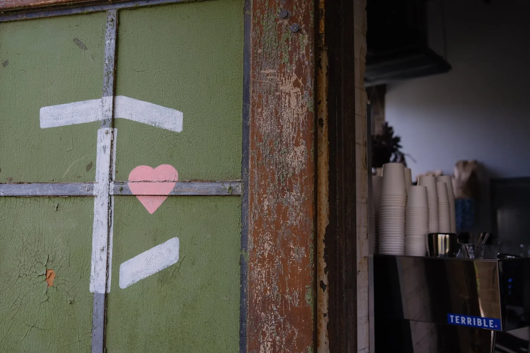 The painted green door at Terrible Love, with a hand-painted white mark and a pink heart